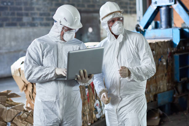 Workers in hazmat suits managing asbestos materials at a recycling facility, emphasizing the importance of asbestos testing and removalist services.